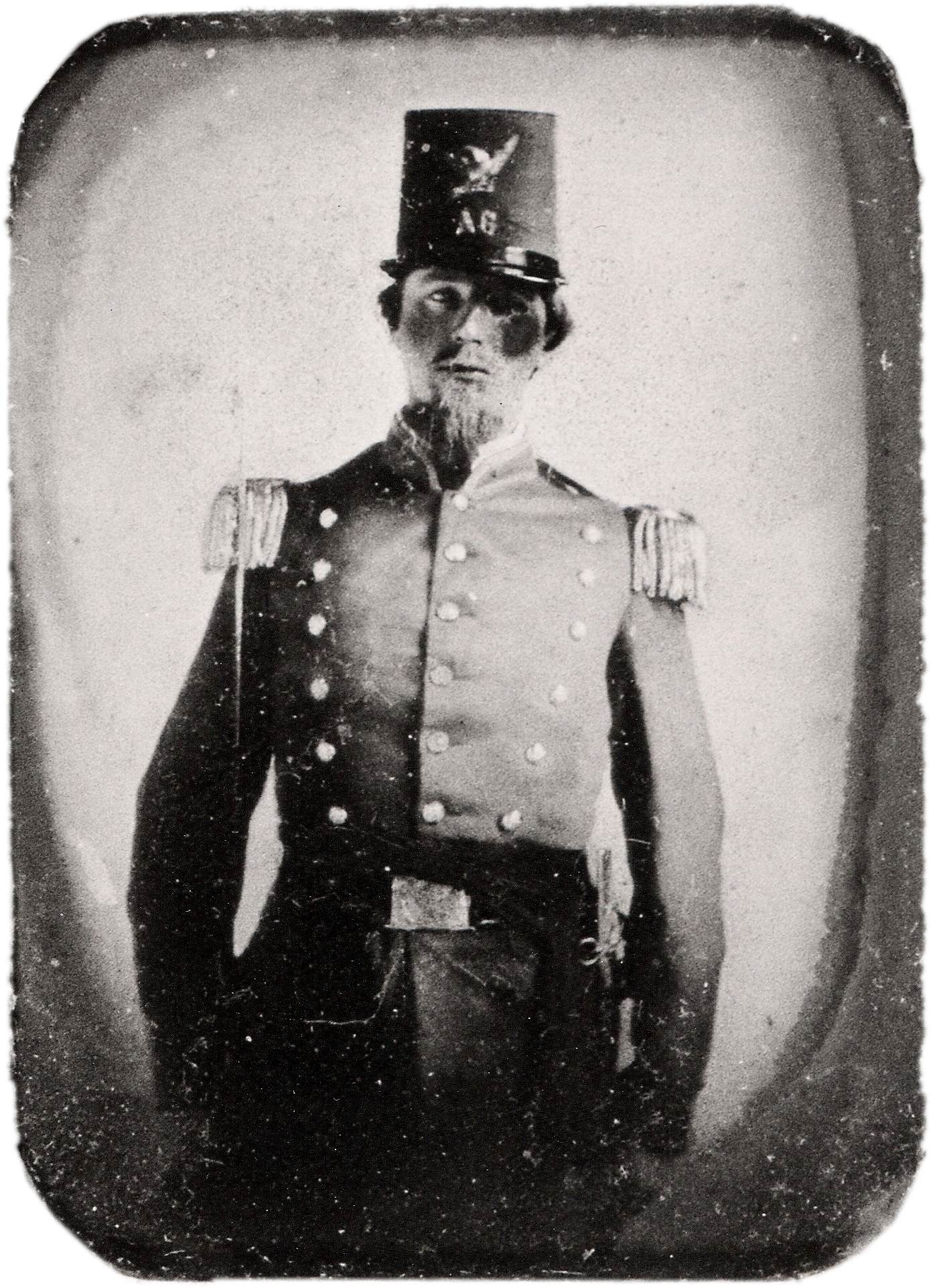 Damaged 19th-century black and white photograph of a militia officer in uniform, with visible scratches and surface deterioration
